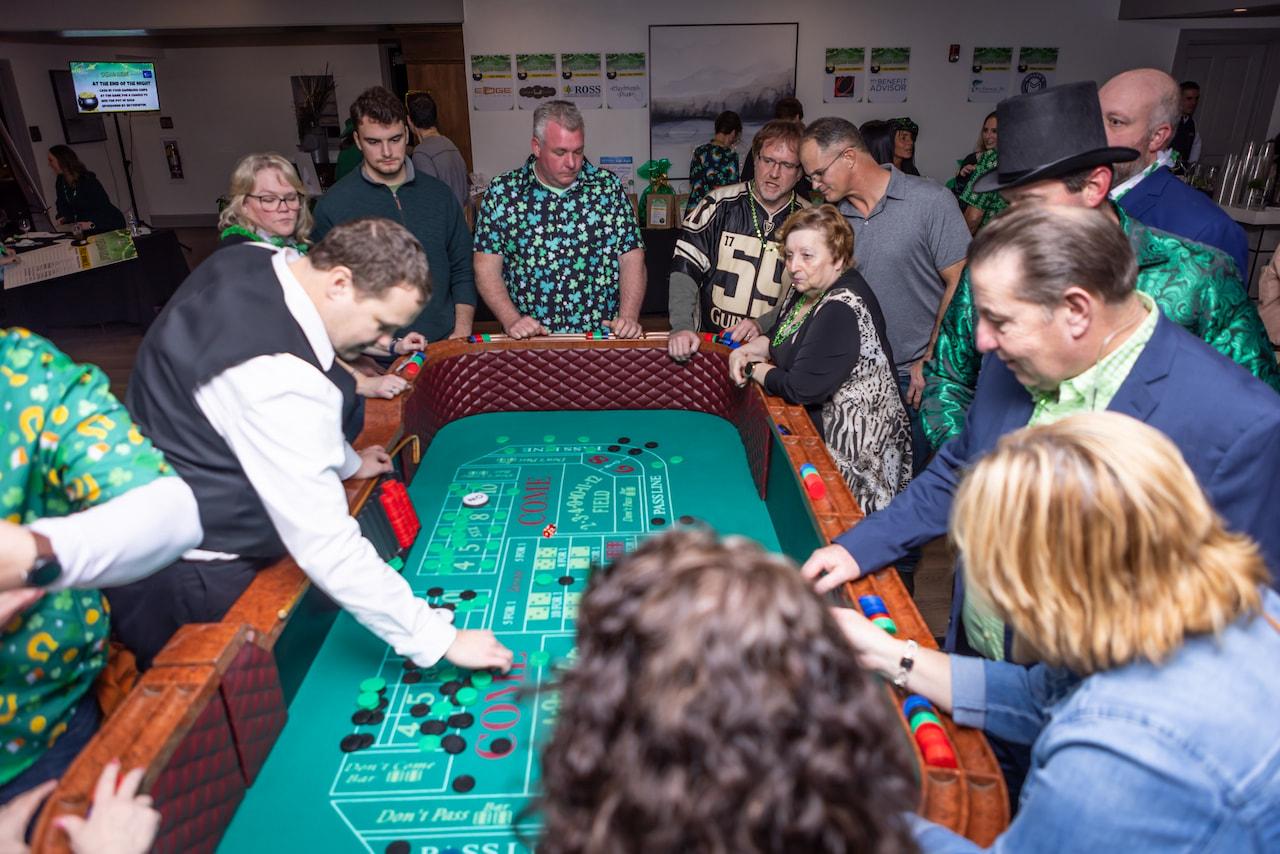 Group of people engaged in a craps game at a casino-themed event.