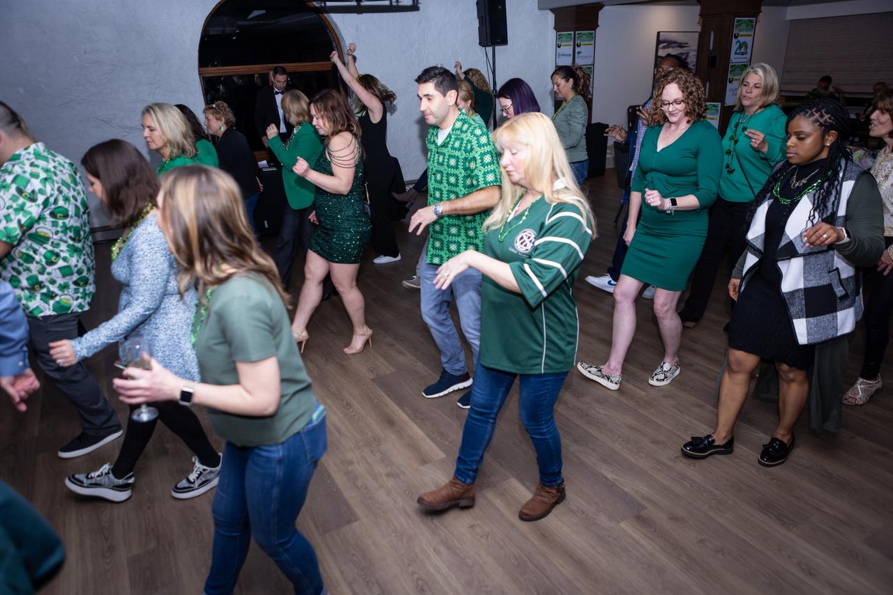 People dressed in green clothing dancing at a saint patrick's day celebration.