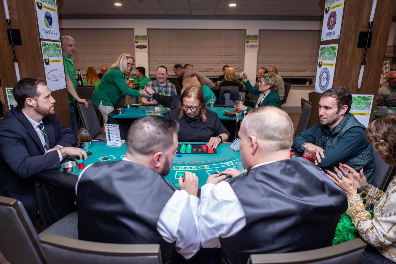 People dressed in green participating in a casino game at a table.