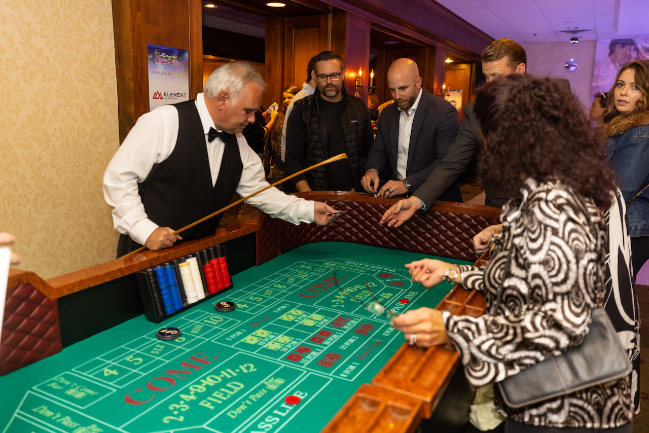 Guests playing craps at a casino event with a dealer managing the table.