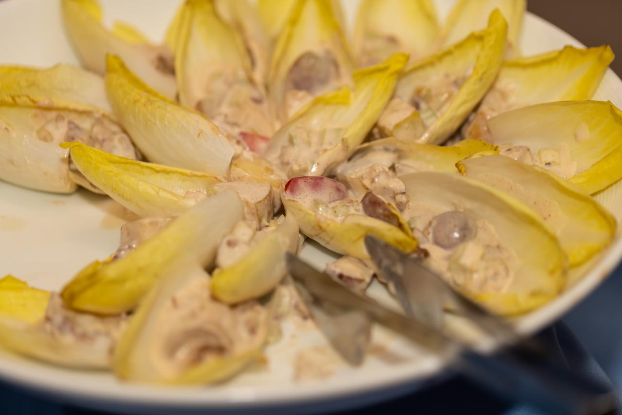 A plate of endive leaves filled with a creamy mixture, potentially a type of appetizer or salad.