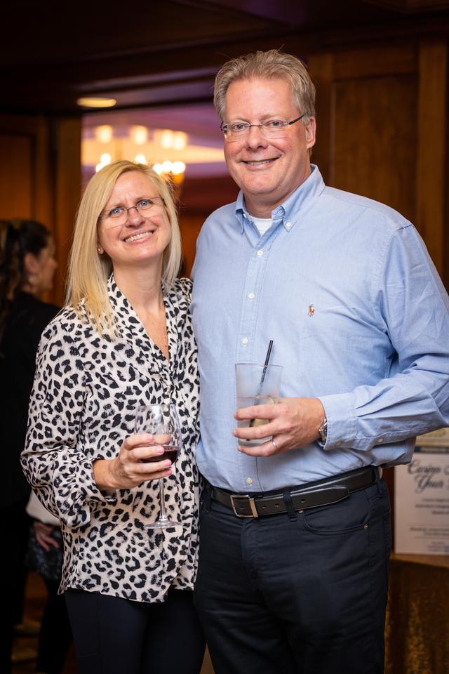 A smiling man and woman holding drinks at a social event.