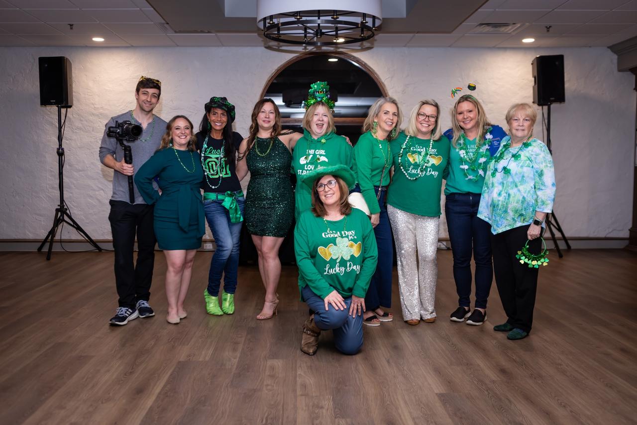 Group of people dressed in green with st. patrick's day themed attire posing together for a photo.